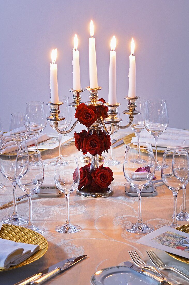 Festlicher Kerzenleuchter mit roten Rosen auf Tisch