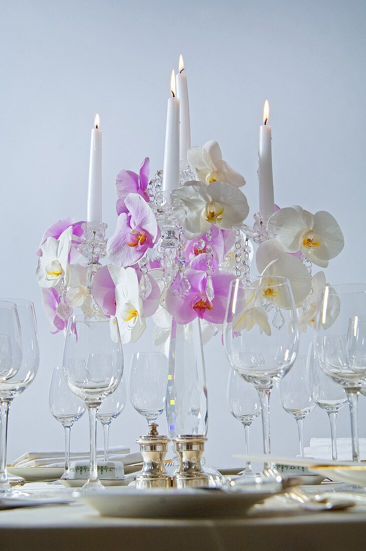 Kerzenleuchter mit Orchideen auf festlichem Tisch