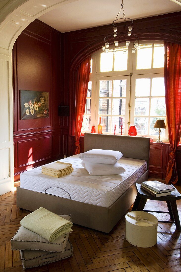 Doppelbett mit Matratze in Schlafzimmer mit roter Wandvertäfelung