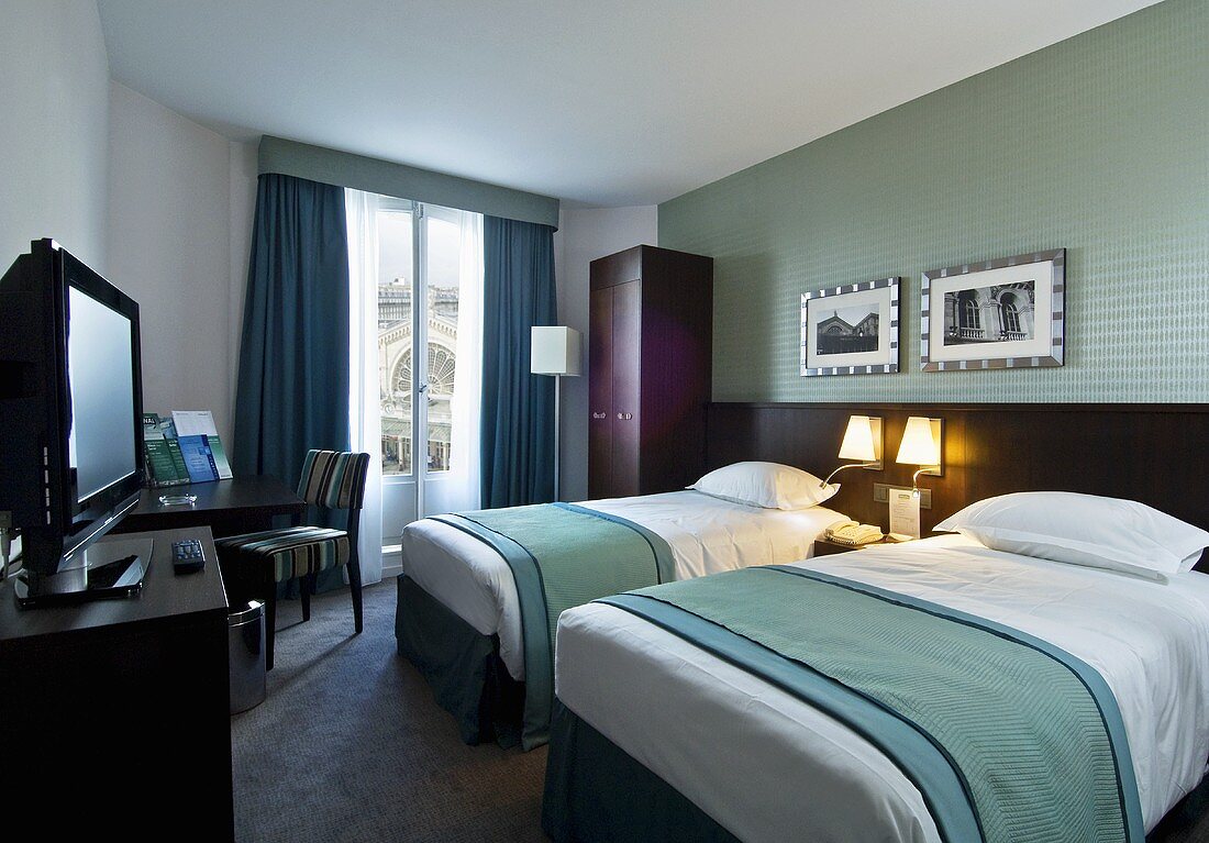Hotelzimmer mit zwei Betten, Fernseher, Schrank & Tisch (Paris, Frankreich)
