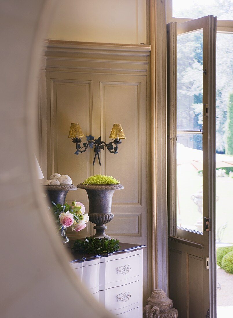 Blick in Spiegel auf Kommode mit Deko-Objekten im Empfangsraum des Schlosses La Verrerie (Frankreich)
