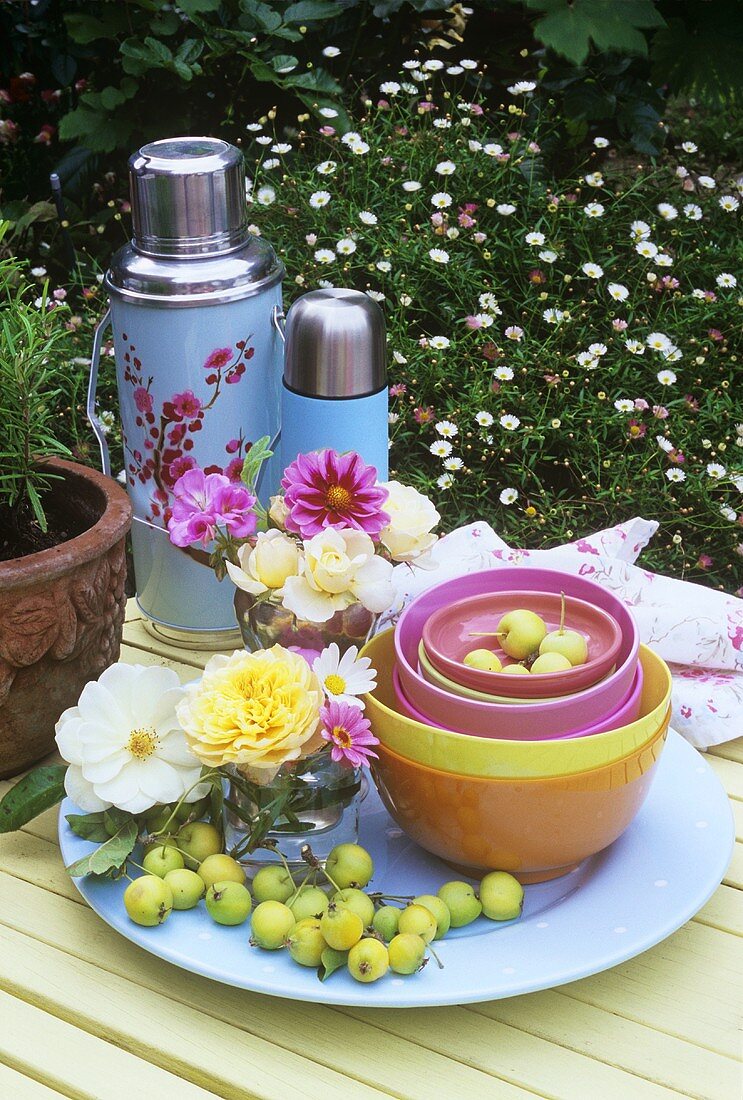 Tisch mit Blumen, Schalen und Thermosflaschen im Freien