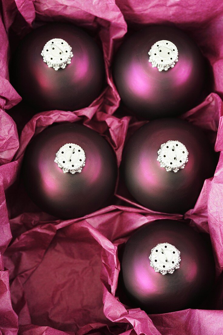 Five purple Christmas baubles in a box