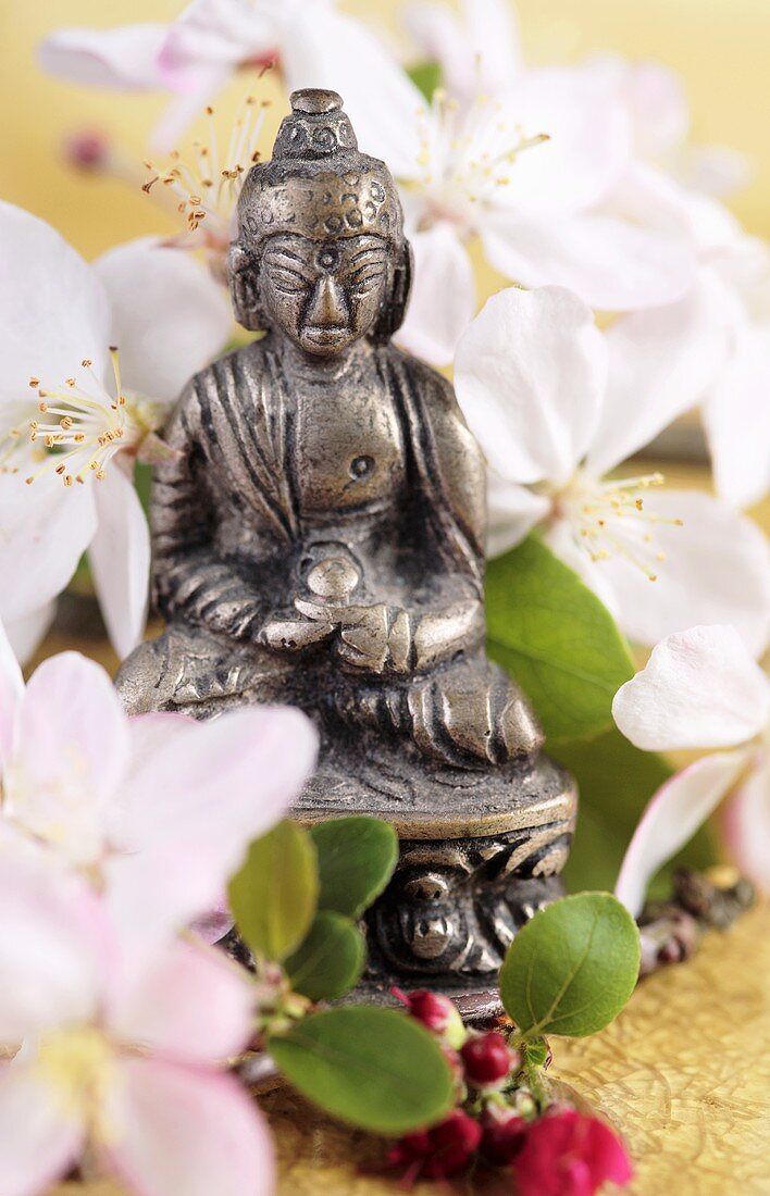 Buddha-Figur mit weissen Blüten