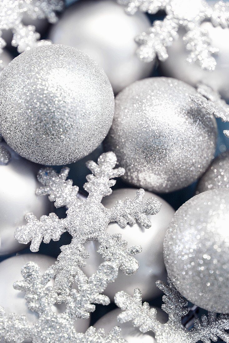 Silberfarbene Weihnachtskugeln und Schneeflocken, bildfüllend