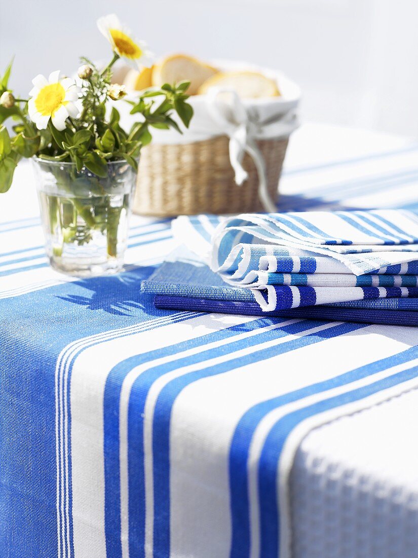 Gedeckter Tisch in Blau und Weiß mit Margeriten und Brotkorb