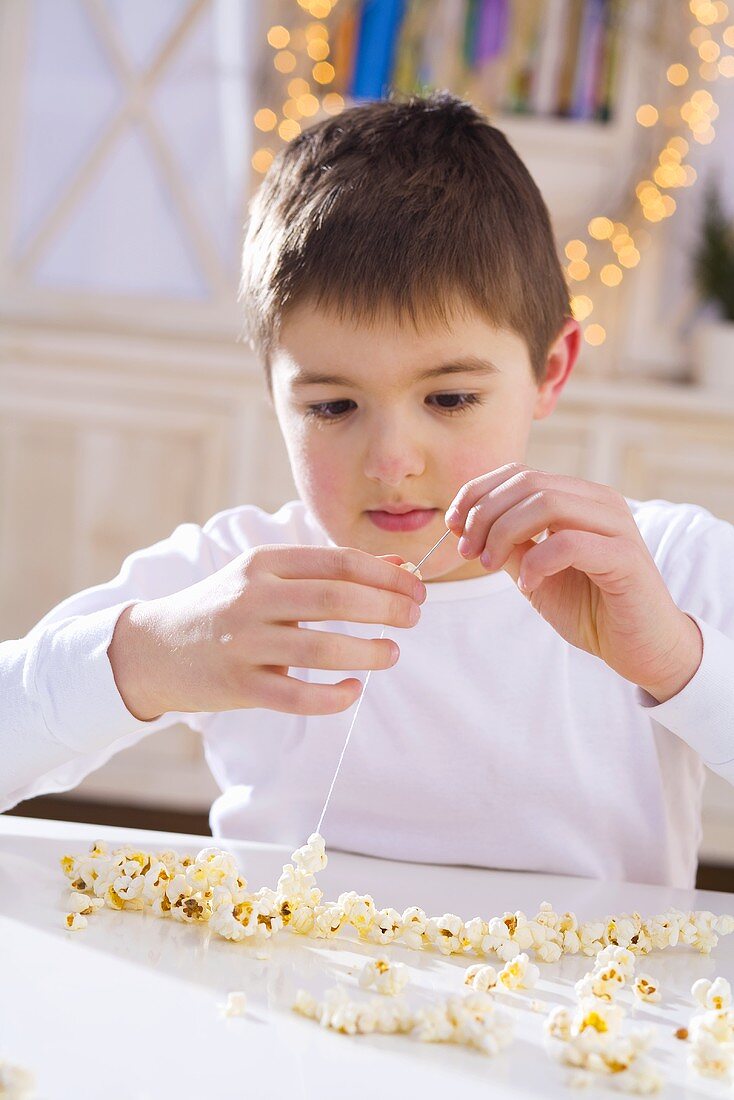 Boy threading popcorn (to make popcorn wreath)