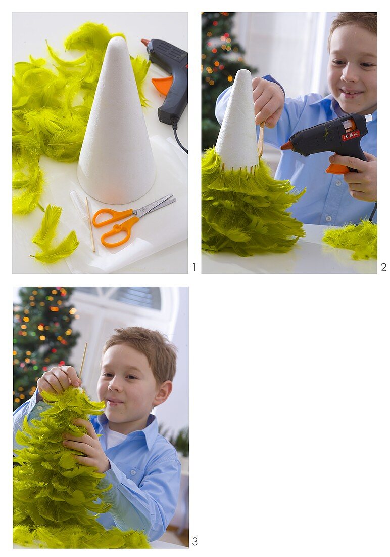 Junge bastelt Weihnachtsbaum aus grünen Federn