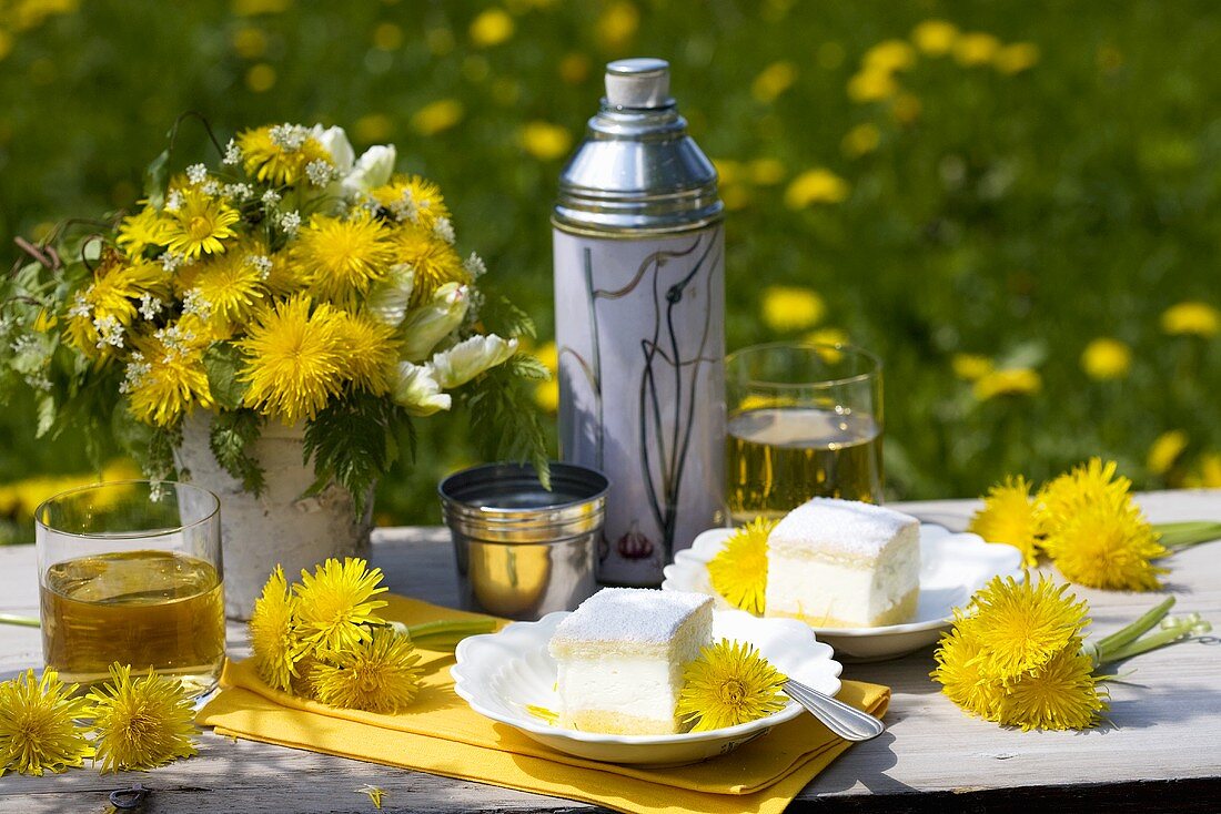 Tisch mit Löwenzahnblüten und Kuchen