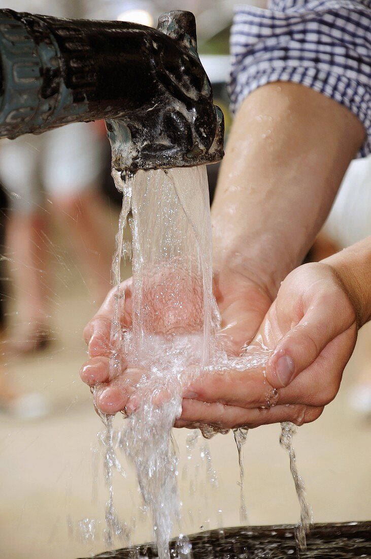 Die Hände an einem Brunnen waschen