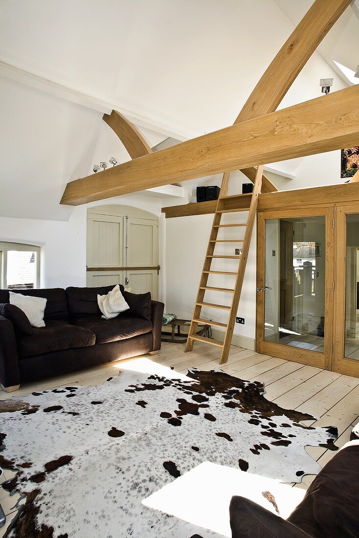 Attic sitting room with couch, cowhide rug, wooden beam