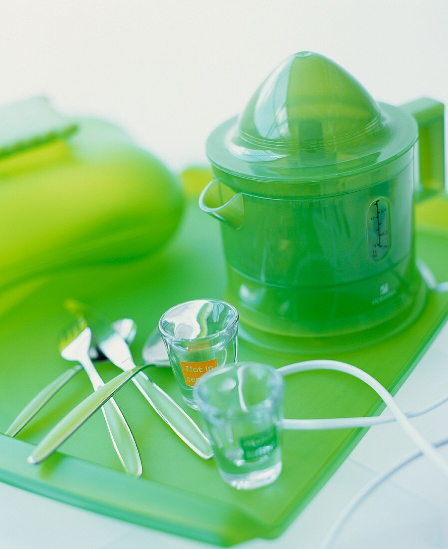 An electric citrus press on a green glass tray