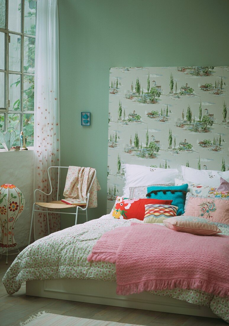 Doppelbett mit Tagesdecke, Zierkissen und tapeziertem Bettkopfteil