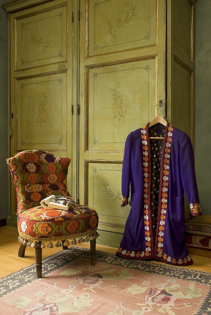 Strickmantel auf Kleiderbügel am Kleiderschrank hängend und antiker Sessel