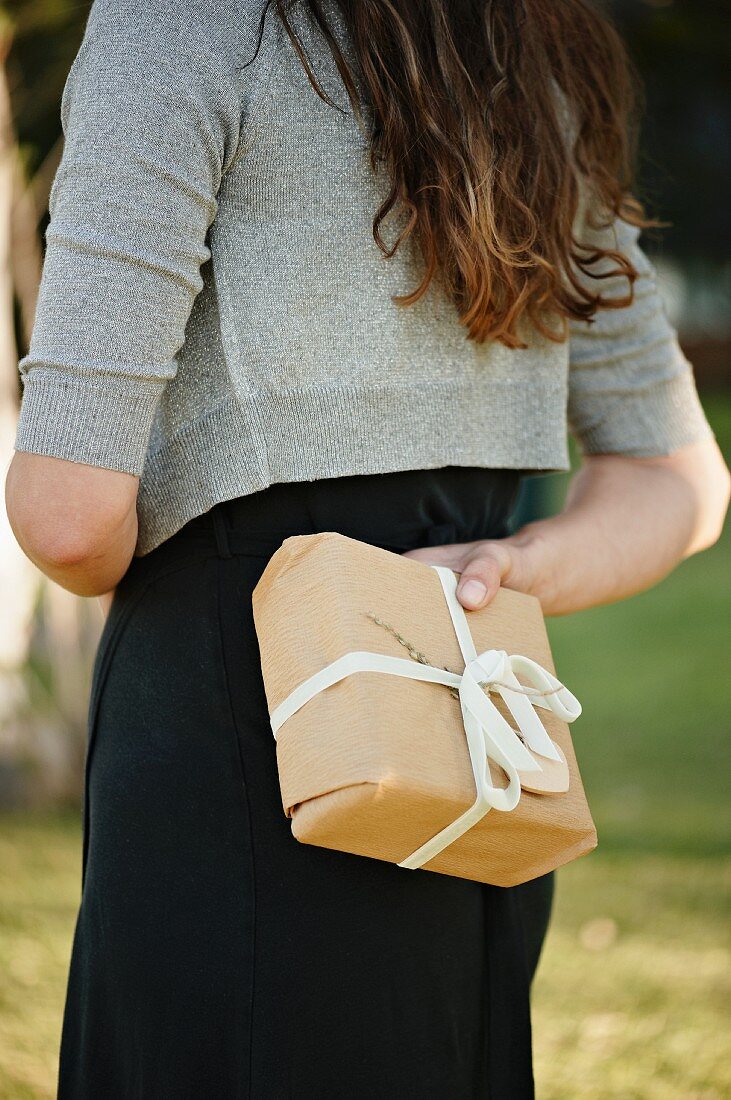 A woman holding a parcel behind her back