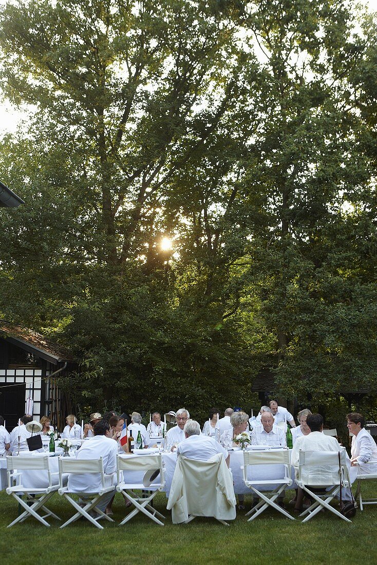 A party in a garden with people sat at white tables