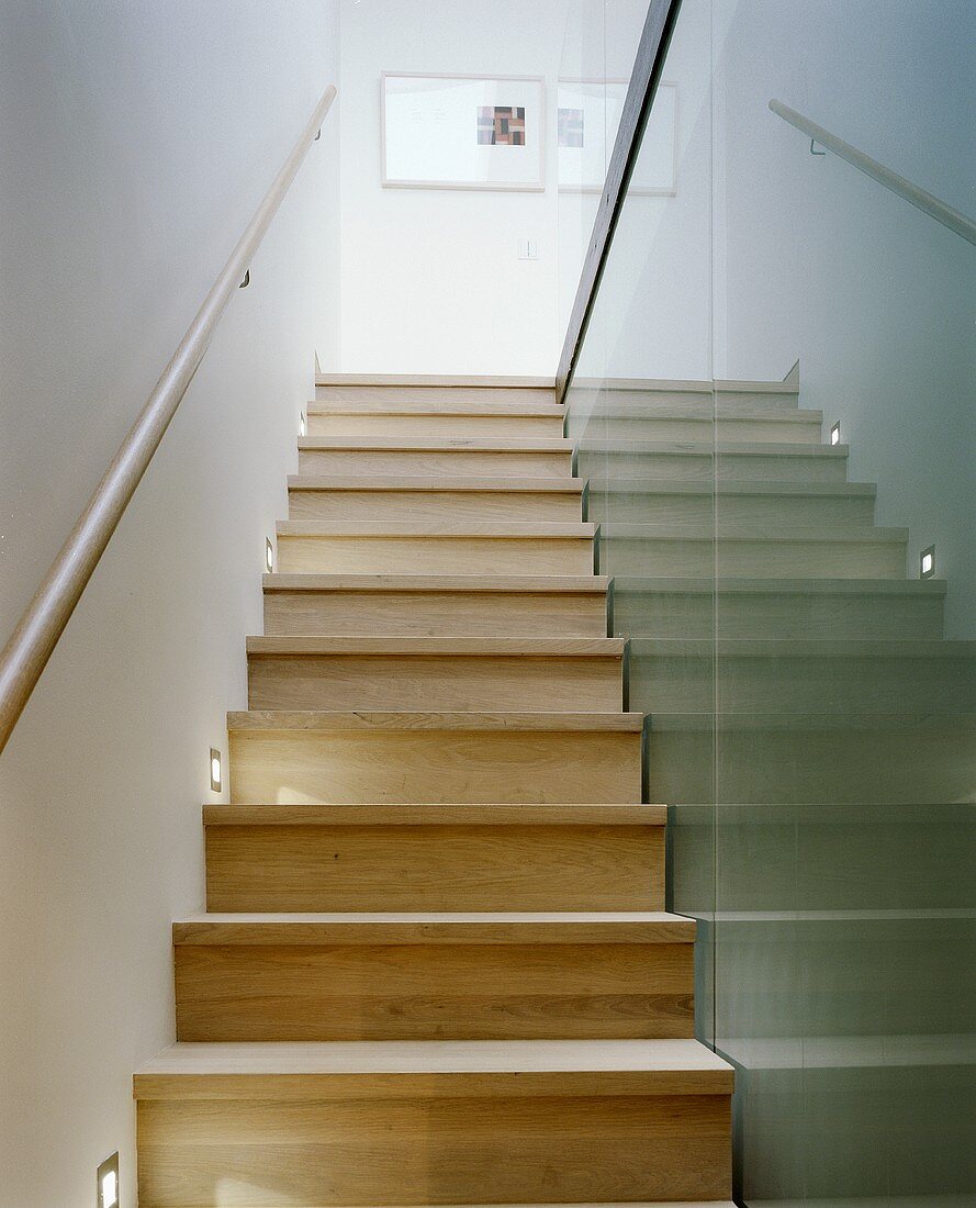 A narrow stairway with wooden steps and a glass partition wall