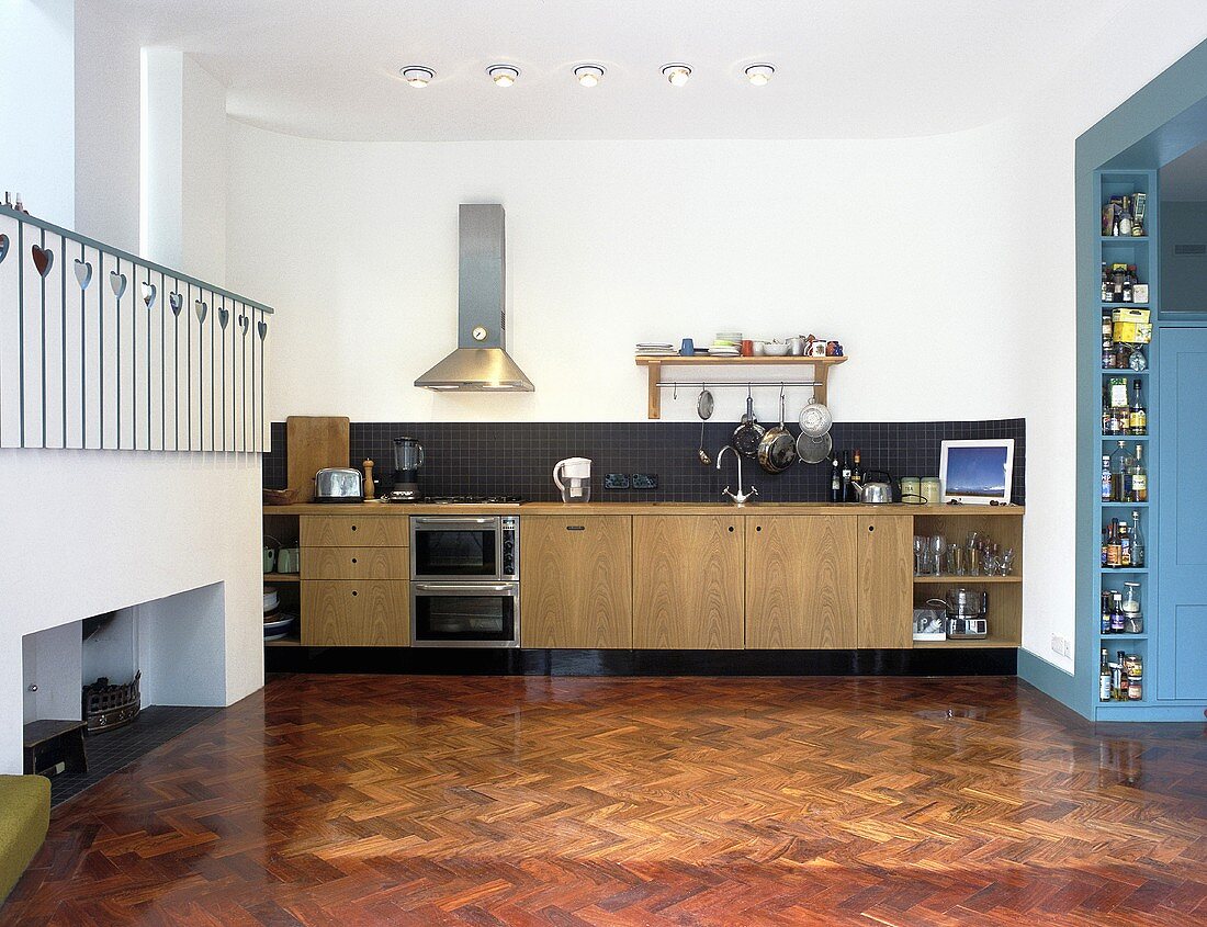Fischgrät-Parkett in offener Küche mit Küchenzeile und Galerie mit weisser Holzbrüstung