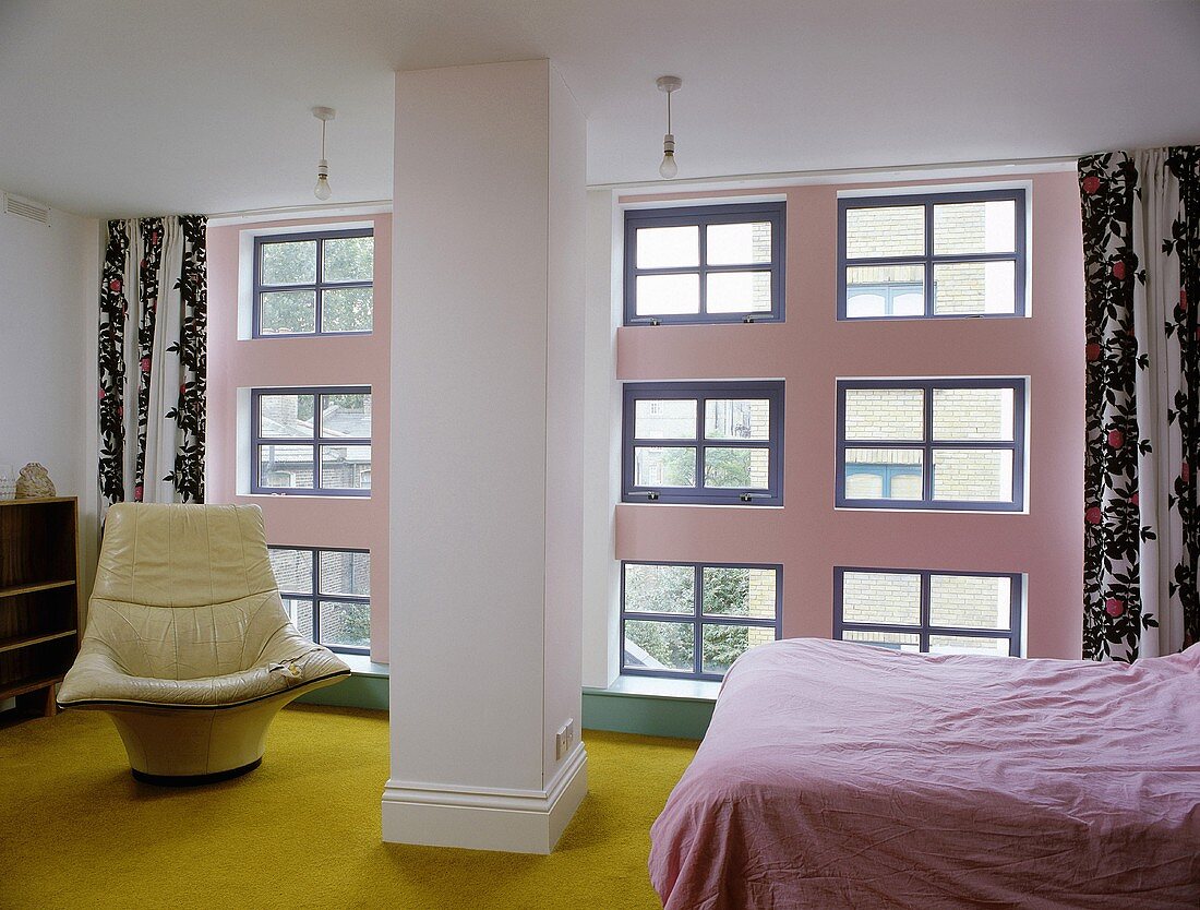 A bedroom with a pillar in front of a window bank with lots of individual windows