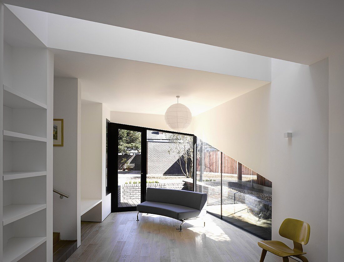 Offener Wohnraum in moderner Architektur mit geschwungenem Sofa auf Parkett