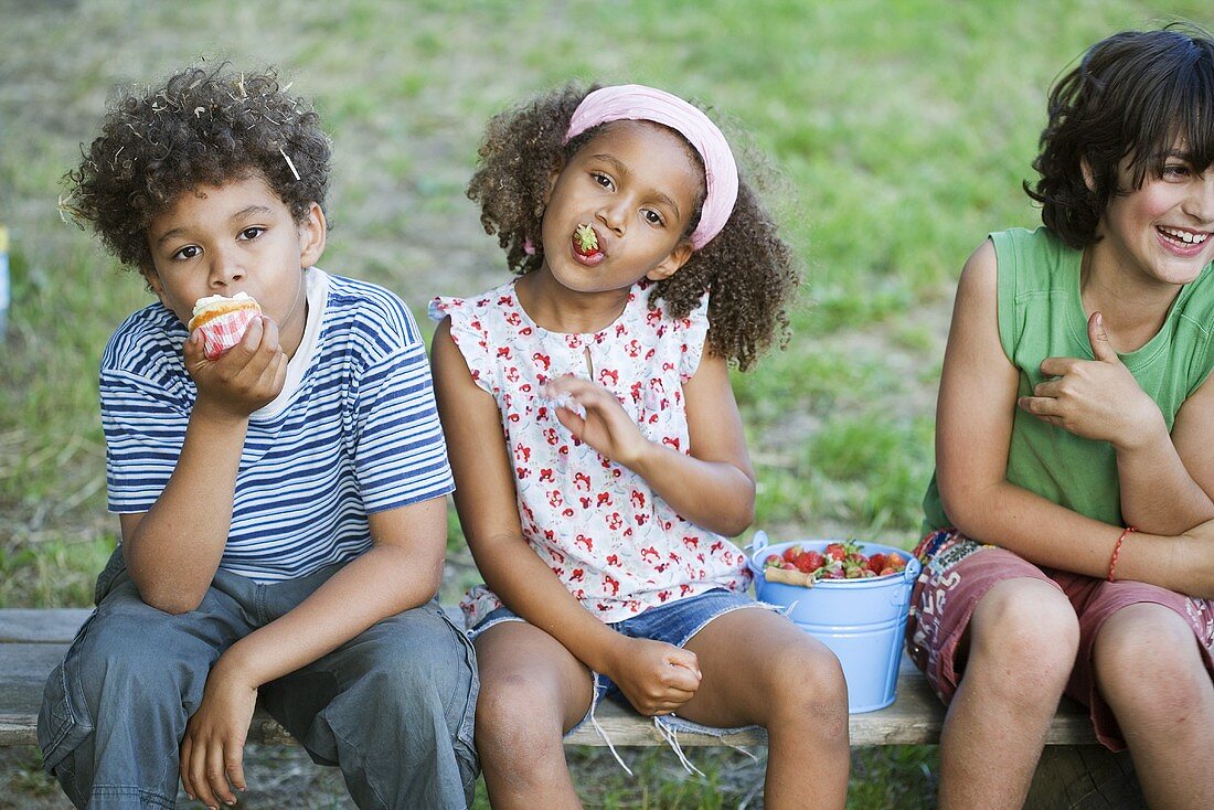 Kinder essen Erdbeeren und Muffin