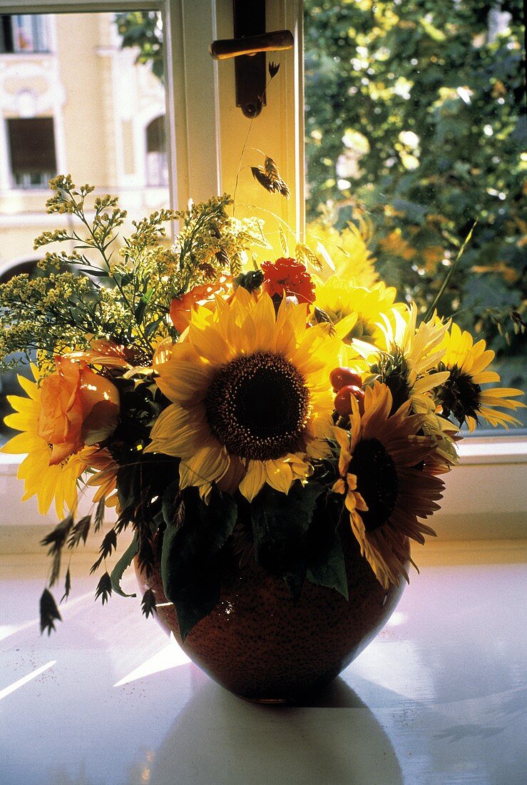 Blumenarrangement mit Sonnenblumen in Vase vor Fenster