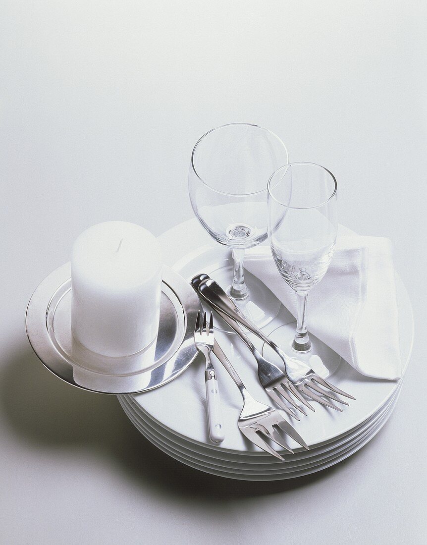 weiße Teller, Gabeln, Gläser, Serviette und Kerze