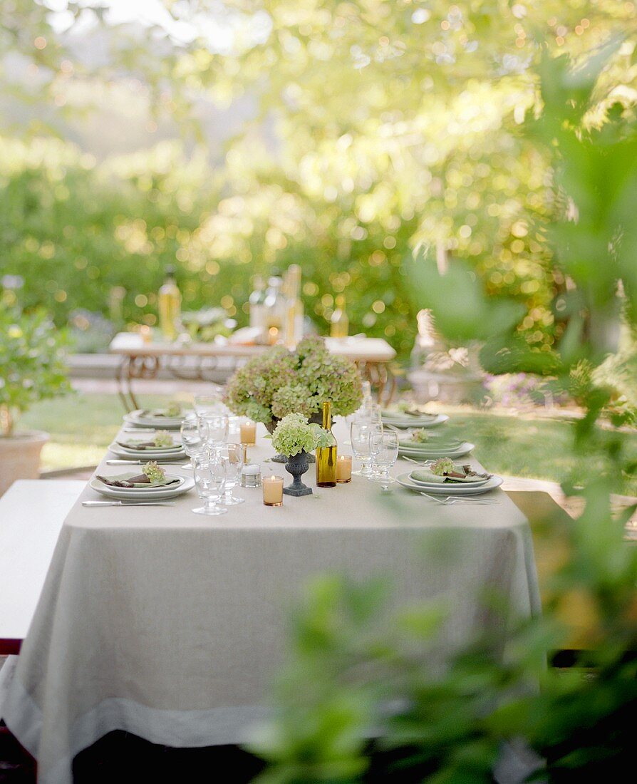 Laid table in the open air with hydrangeas and candles