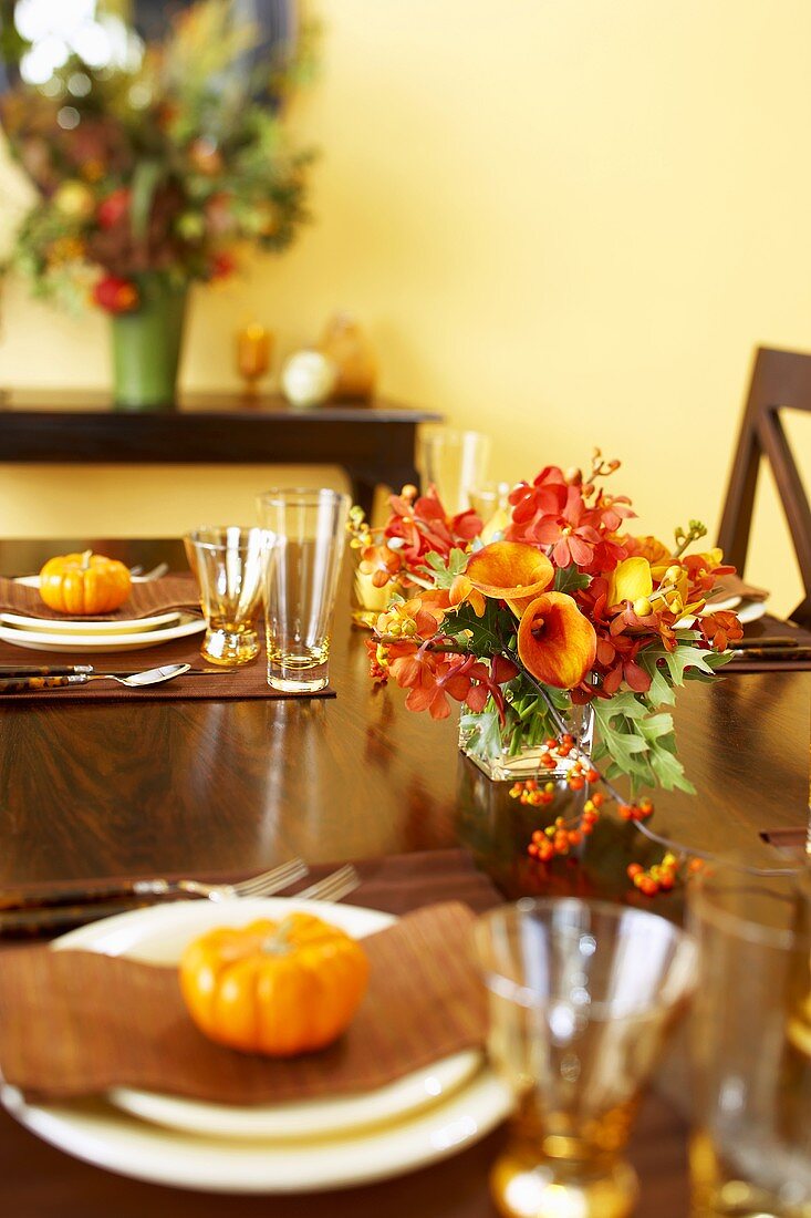 Herbstlich gedeckter Tisch mit Blumen und Zierkürbissen