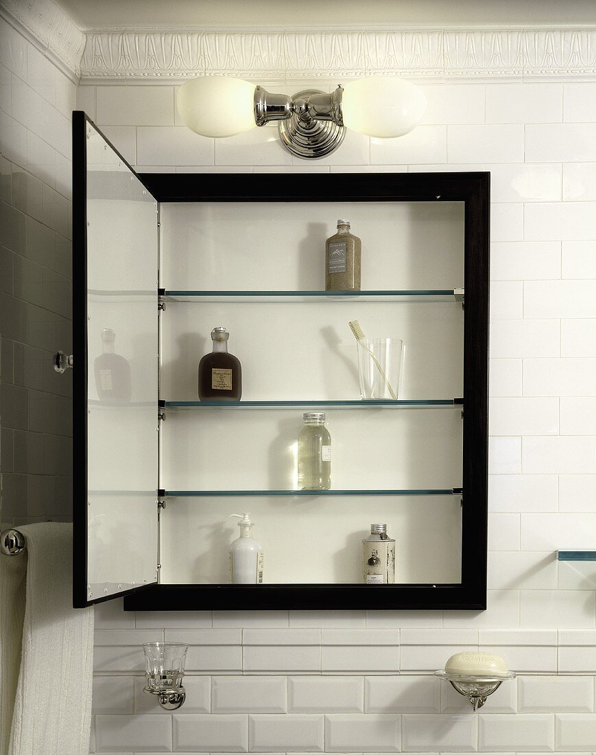 Geöffneter Badschrank mit schwarzem Rahmen an weisser Ziegelfliesenwand