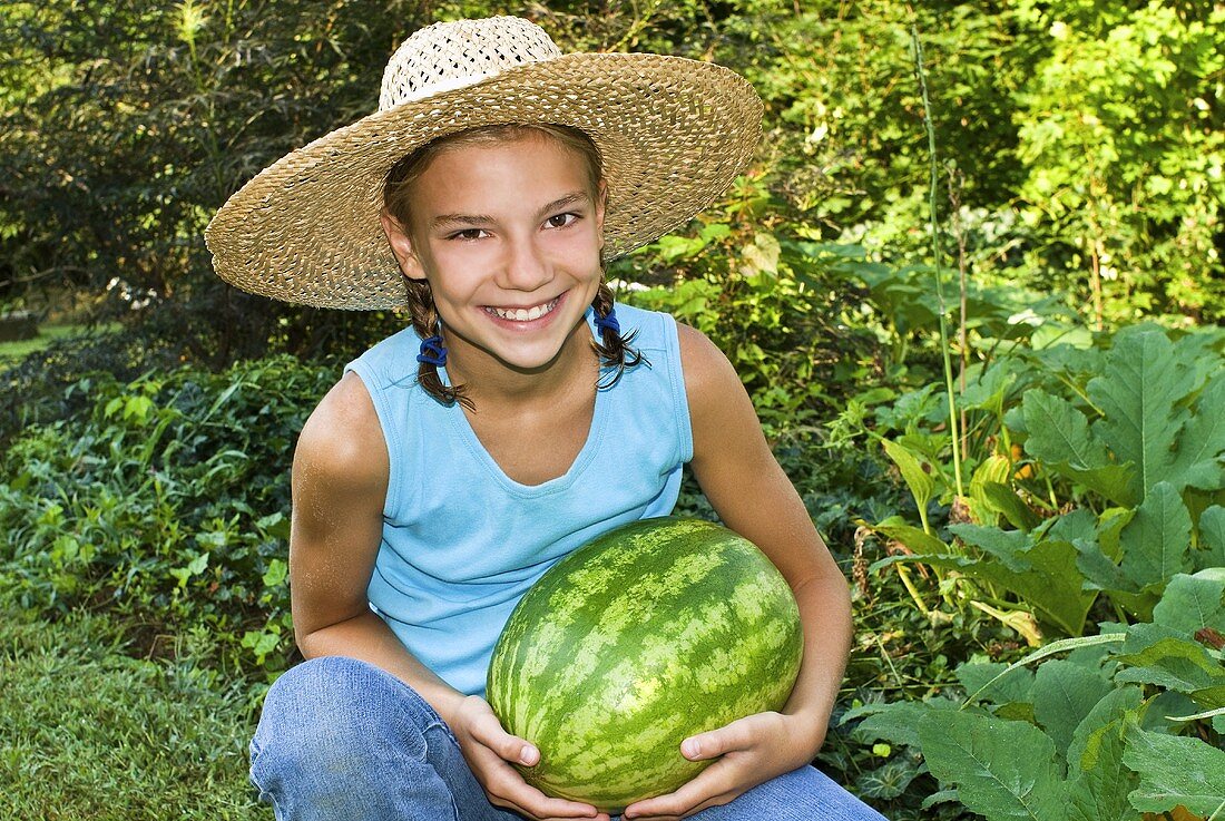 Mädchen hält frisch geerntete Wassermelone im Garten