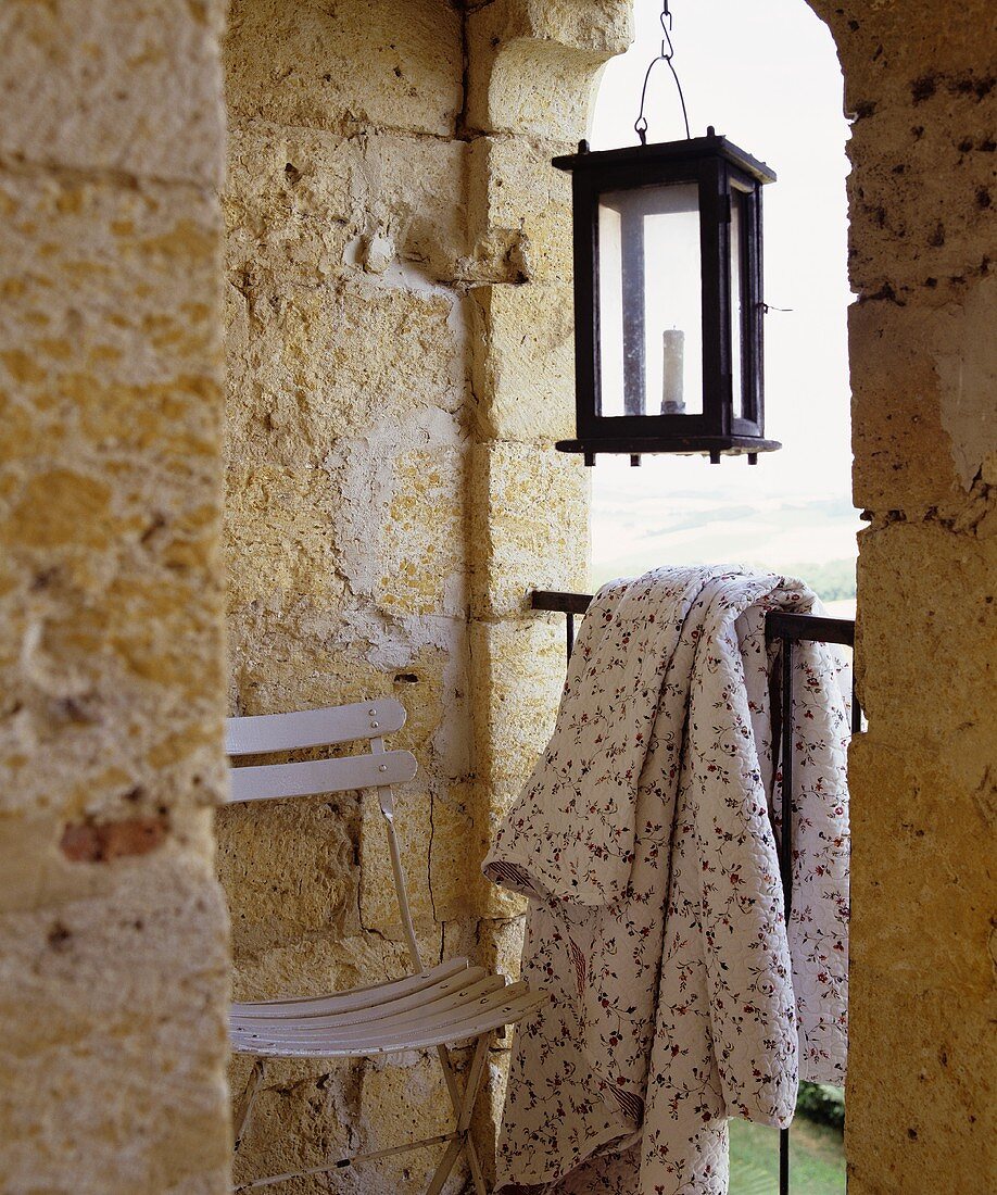 Kleine Loggia mit Stuhl, geblühmter Sommerdecke und Laterne