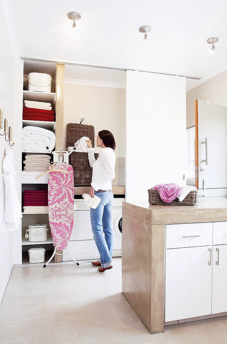 Frau macht Wäschearbeiten im hellen geräumigen Wirtschaftsraum