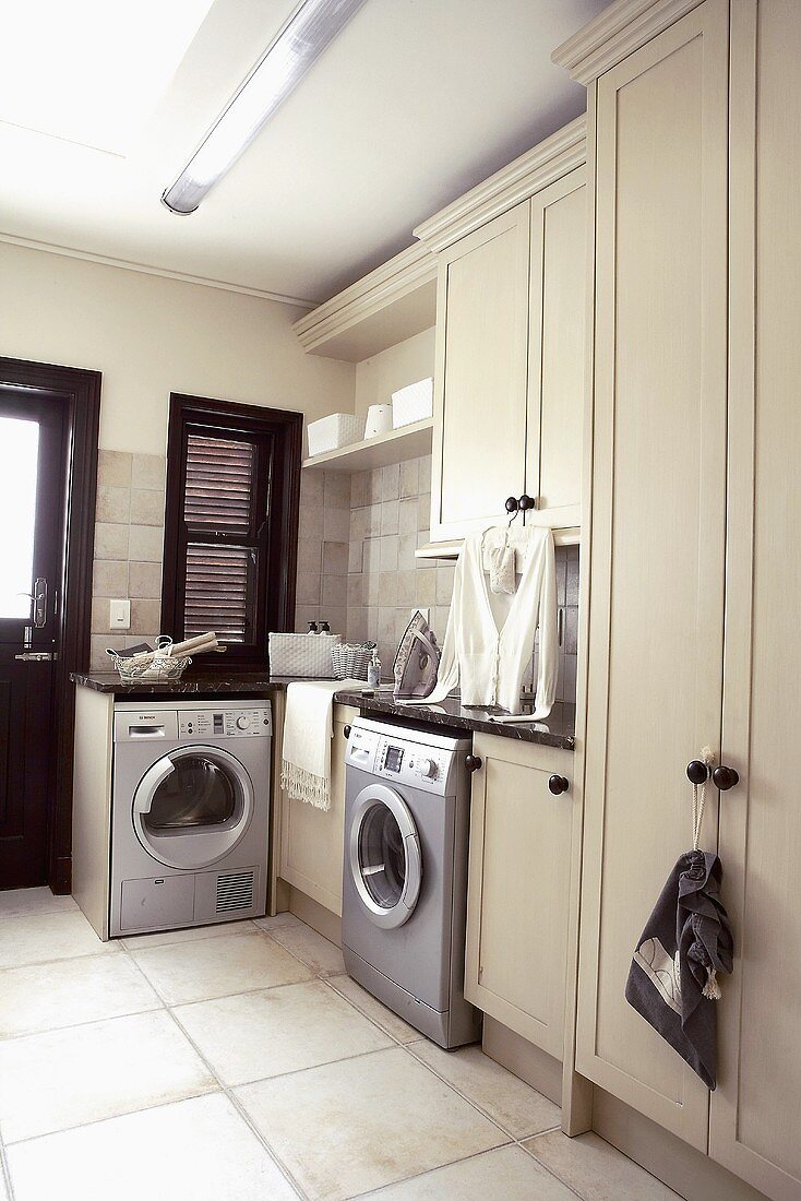 Stainless steel washing machines in a spacious, sand-coloured utility room
