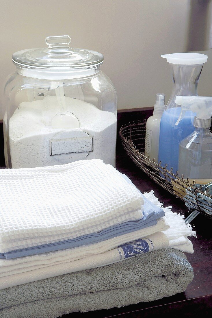 bereitgestellte Waschmittel in Behältern aufgefüllt, davor gestapelte Wäsche