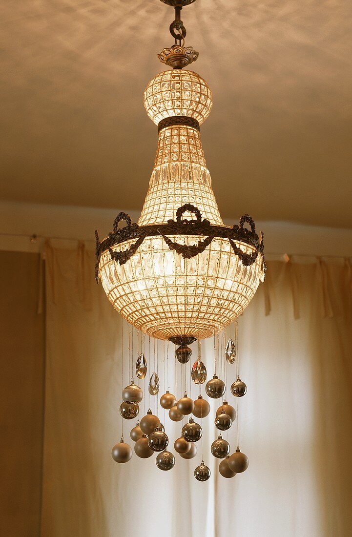 A crystal chandelier decorated with Christmas baubles