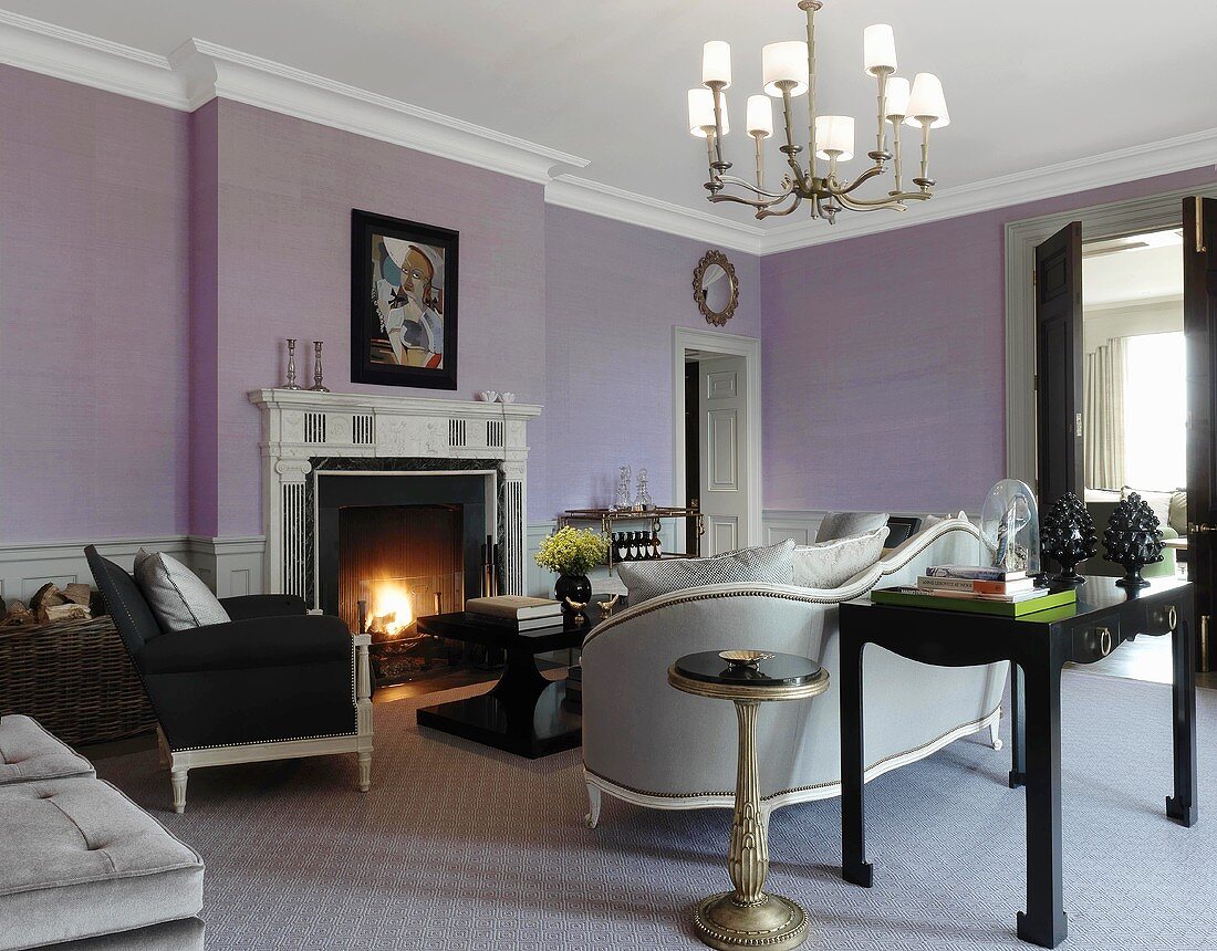 Elegantes, violettfarbenes Wohnzimmer in traditionellem Haus, mit erlesenen Möbeln und einem brennenden Kaminfeuer