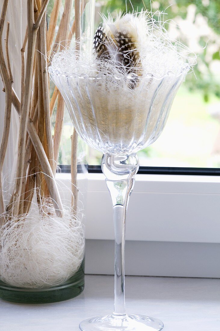 A stemmed glass filled with white straw with decoration