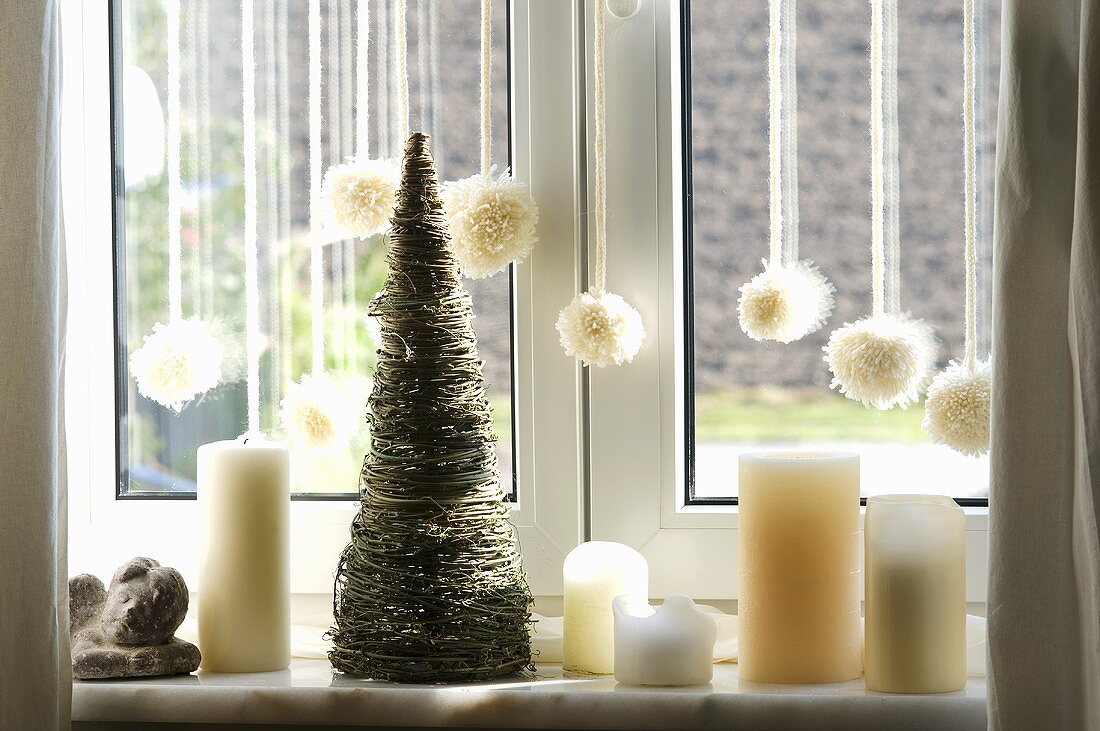 weiße Fensterdeko dekoriert mit Kerzen