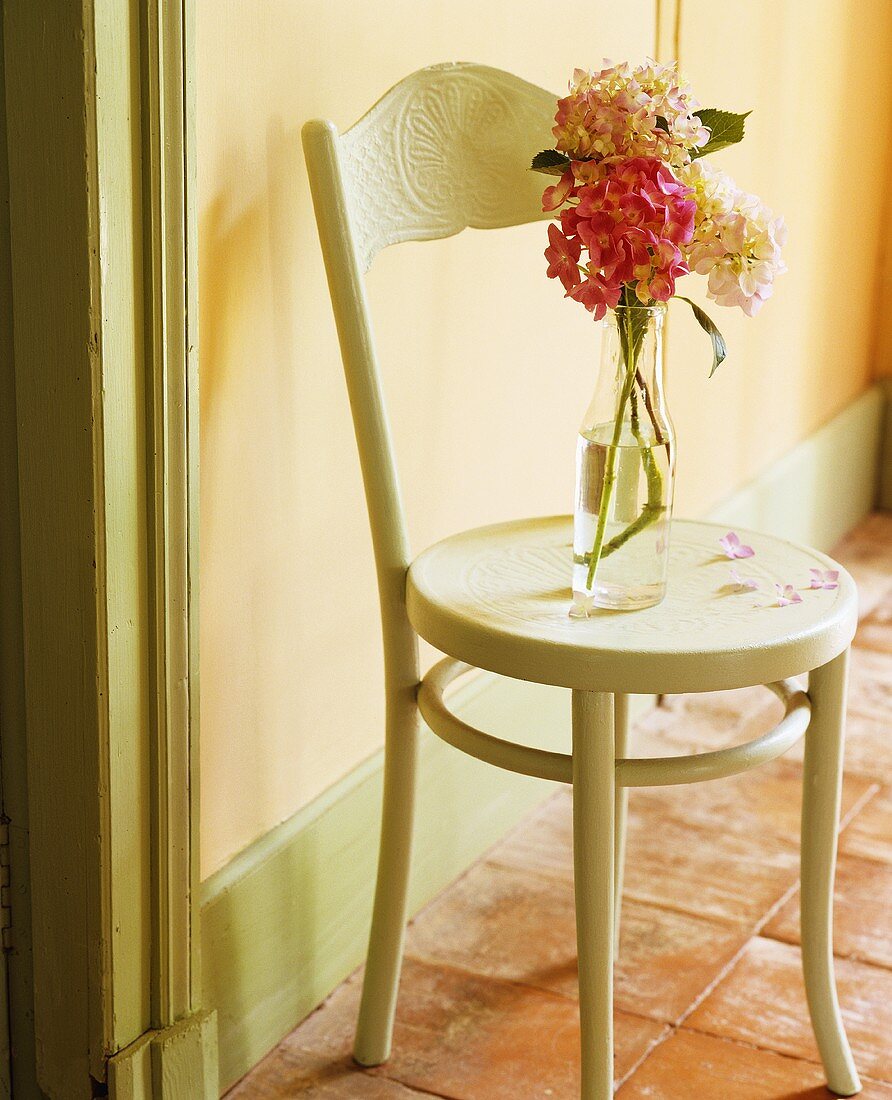 A vase of flowers on an old wooden chair