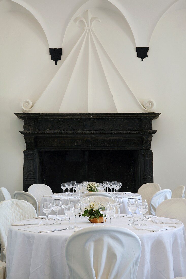 Festively laid table with a white cloth in front of an open fire