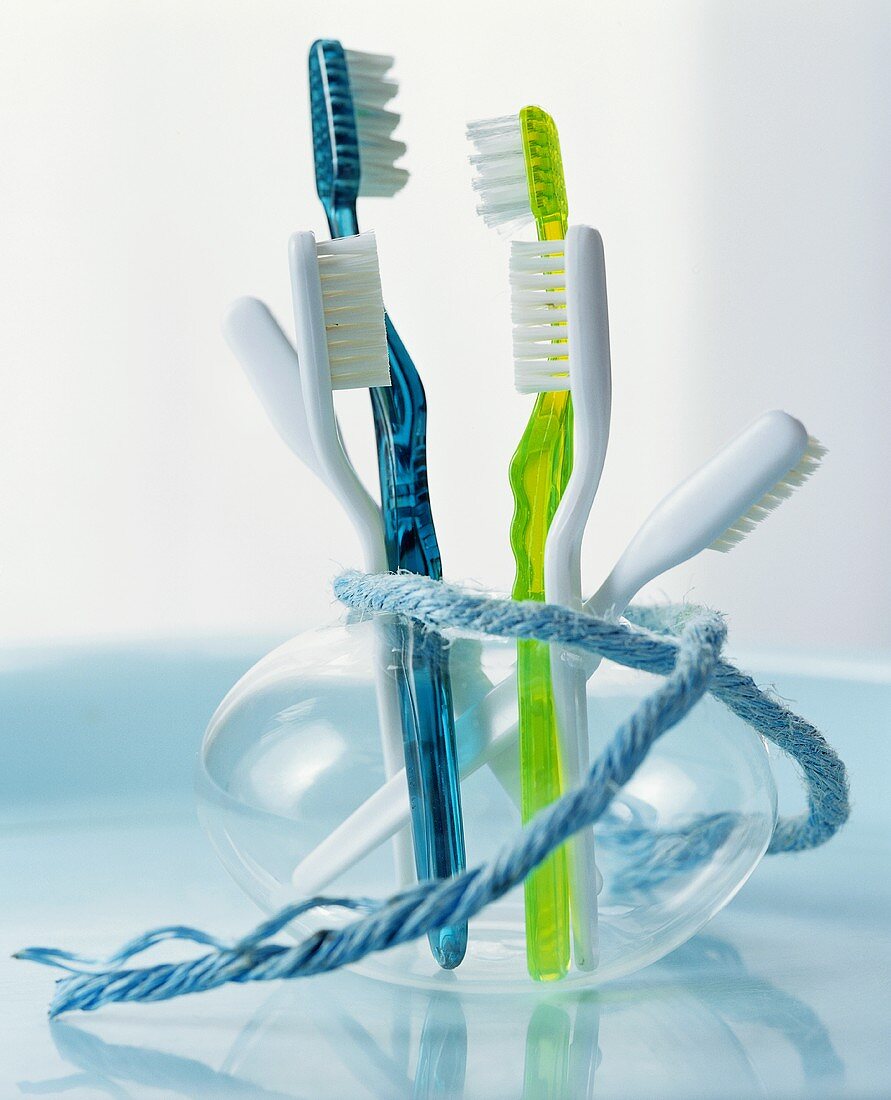 Farbige Zahnbürsten in einer Glasvase mit einem Band umwickelt