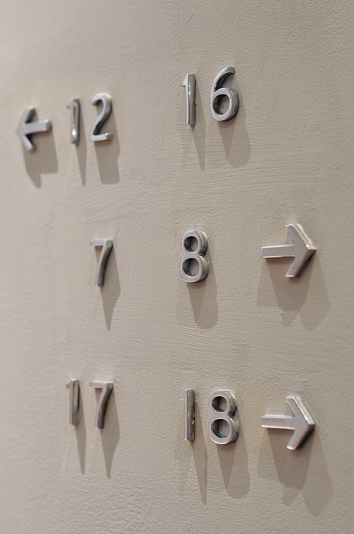Zahlen mit Richtungspfeilen an einer weissen Wand befestigt
