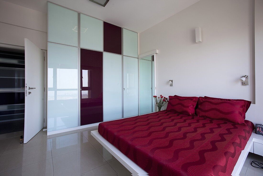 A large bedroom with a bed with red bed clothes
