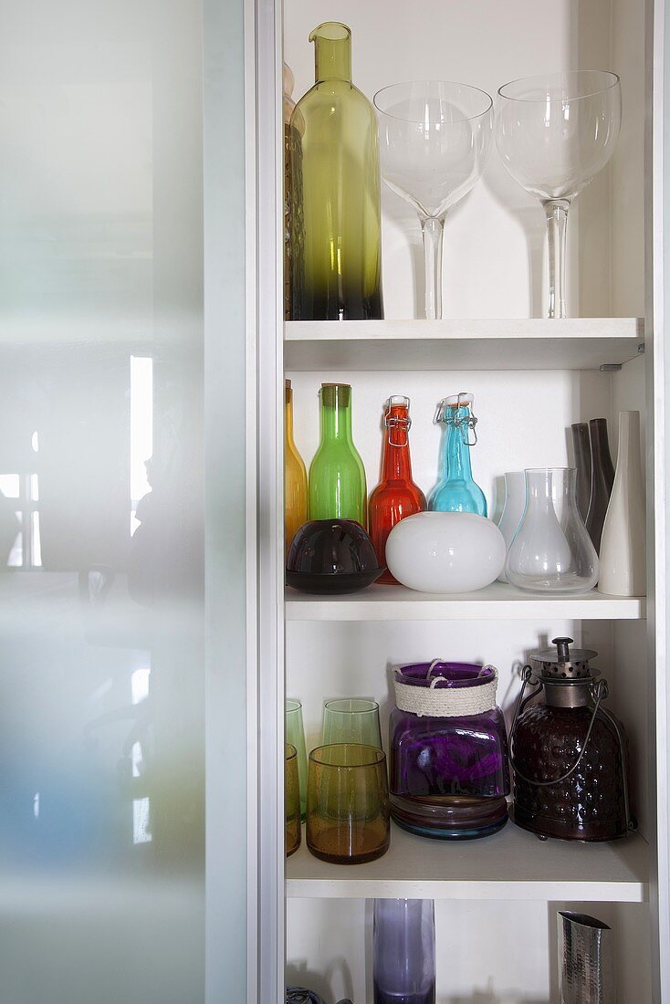 A cupboard filled with coloured glass bottles (cropped)