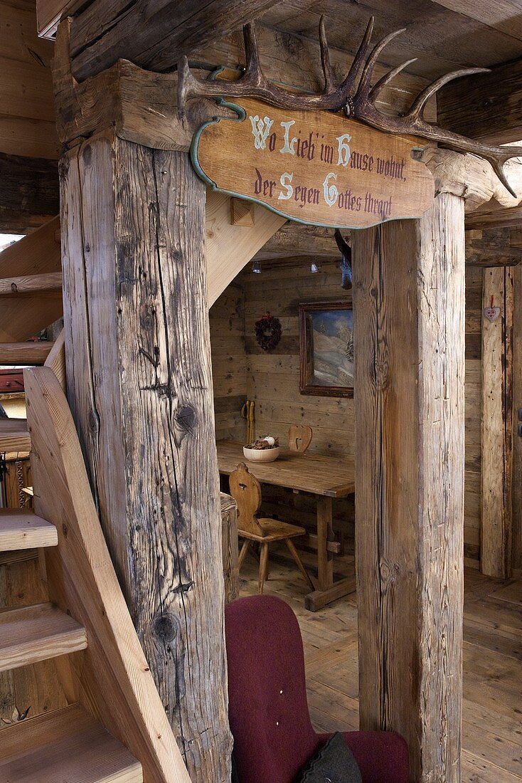 A view into a wooden hut with a rustic interior and antlers on a wooden beam