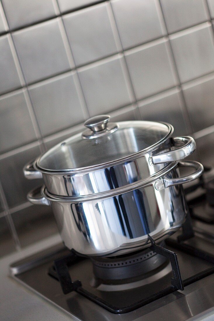Stainless steel pots stacked on a gas hob