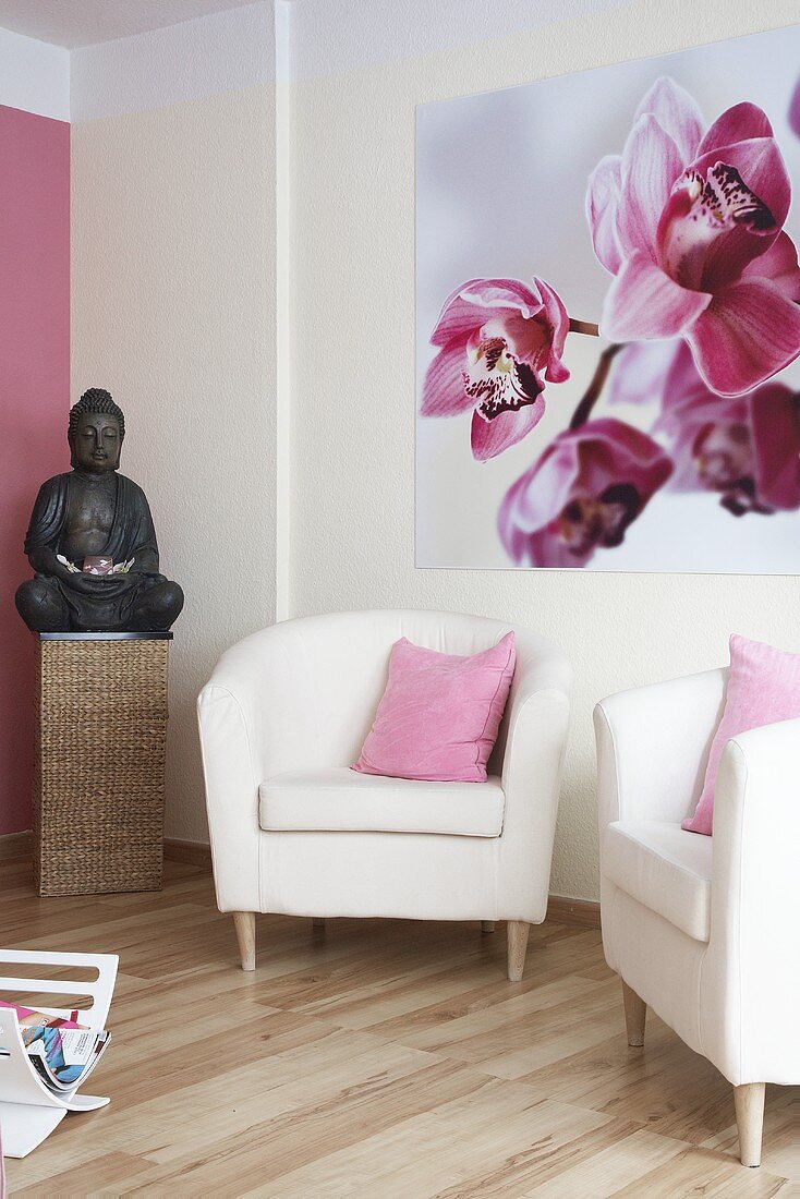 weiße Sessel, Buddhafigur & Wandbild mit Orchideen-Motiv in einer Praxis
