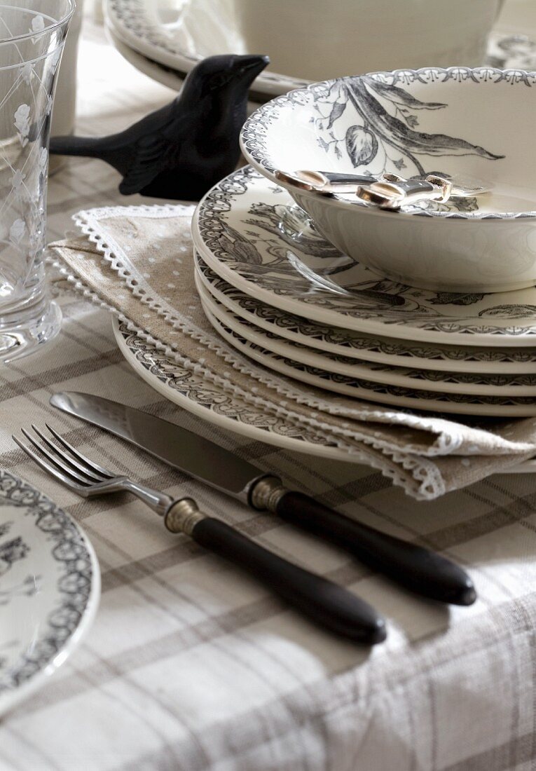 A stack of plates and cutlery on a table cloth