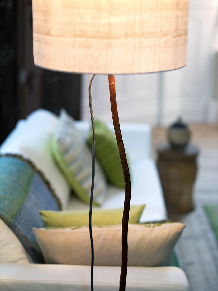 Stehlampe mit hellem Papierschirm vor Sofa